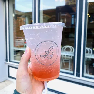 a hand holding a plastic cup with a drink in it
