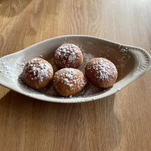 a bowl of powdered sugared doughnuts