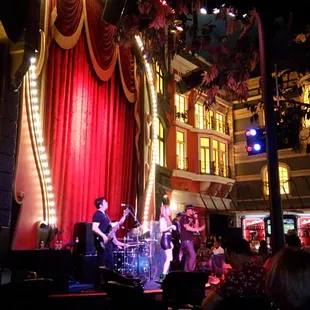 a band performing in front of a red curtain