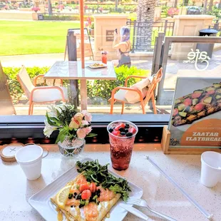 salmon crepe and mixed berry soda with view of outdoor seating