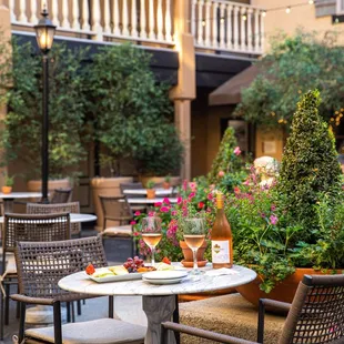 A table with two wine glasses on it, grapes and crackers at Le Chateau Garden Bistro, Costa Mesa.