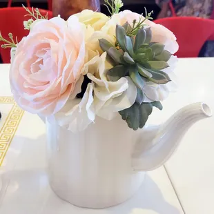 a white teapot with flowers in it