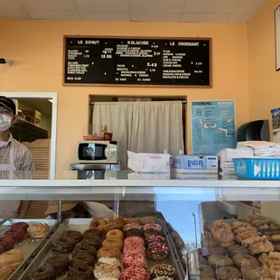 a man wearing a face mask behind the counter of a donut shop