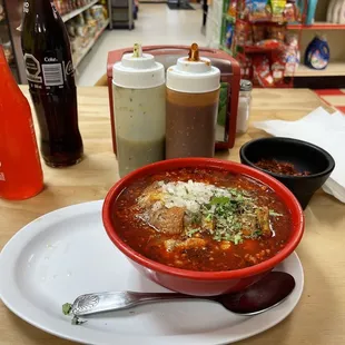 Menudo is prepared with the onions and cilantro red chilly flakes.  Tall coke and a watermelon Jarrito.