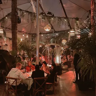 people sitting at tables under an umbrella