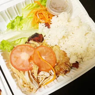 a tray of food with rice, meat, and vegetables