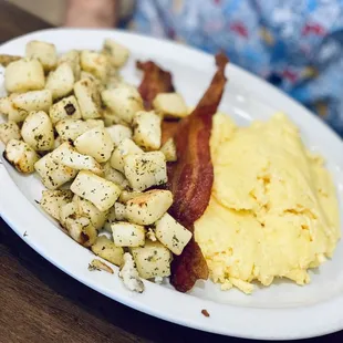 a plate of eggs, potatoes and bacon