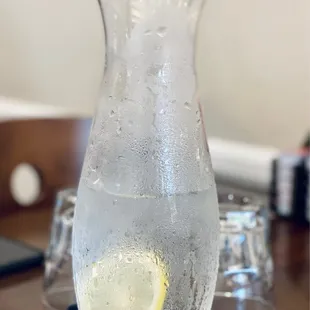 a pitcher of water with a slice of lemon