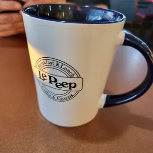 a person holding a cell phone and a coffee mug