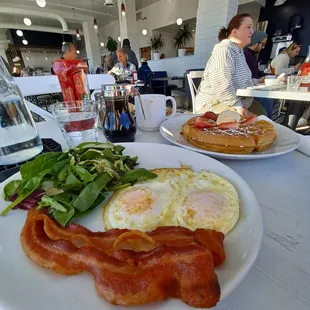 a plate of bacon, eggs, and spinach