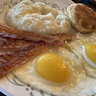 Sunny side up eggs, bacon biscuits, and grits