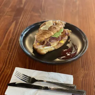 a croissant sandwich on a plate with a fork and knife