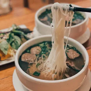 a bowl of soup with noodles and meatballs