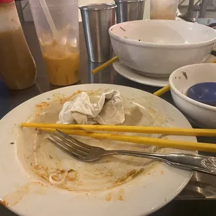 a dirty plate of food with chopsticks