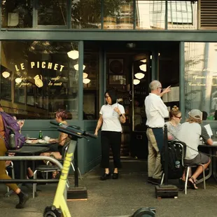 people sitting at tables outside a restaurant