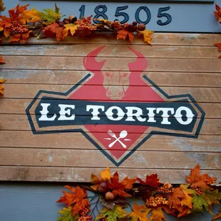 a wooden sign with leaves around it