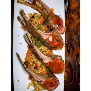 a plate of lamb chops with corn and tomatoes