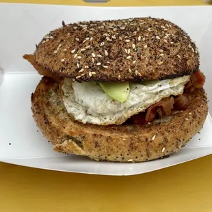 a sandwich in a paper container on a yellow table