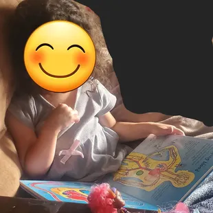 Enjoying her new book, reading to her dolls.