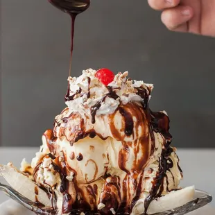  a hand drizzling a cherry on top