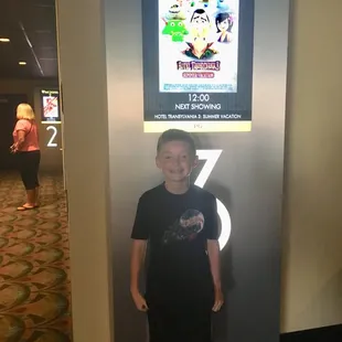 a young boy standing in front of a sign
