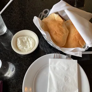 a plate of bread, a bowl of yogurt, and a glass of water
