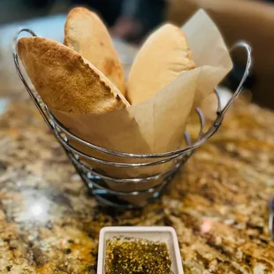 a basket of pita bread and dipping sauce