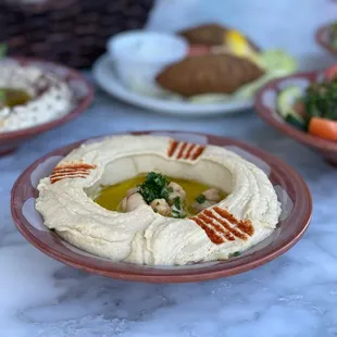 a hummusl with olives and tomatoes