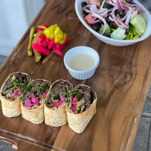 a plate of burritos and a bowl of salad