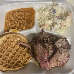 Sliced brisket on a waffle bun with baked beans and coleslaw.