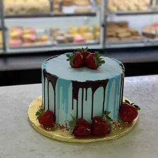 a chocolate drip cake with strawberries on top