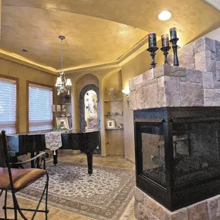 a living room with a fireplace and piano