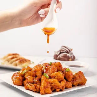a person dipping sauce over a plate of food