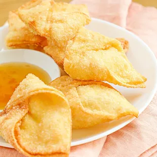 a plate of wontons with dipping sauce