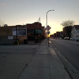 the sun setting on a street corner