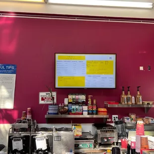 a restaurant counter with a menu on the wall