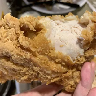 a hand holding a piece of fried chicken