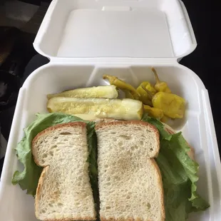 Turkey and cheese on sourdough with a side of chewed up looking pickles and some pepperoncinis.