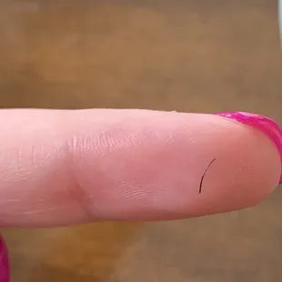 a person&apos;s finger with pink nail polish