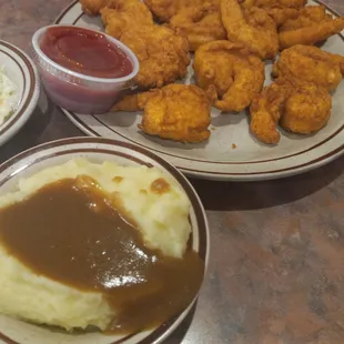 a plate of chicken nuggies, mashed potatoes, and gravy