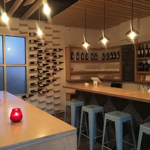 a bar with stools and bottles of wine
