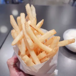 a hand holding a basket of french fries