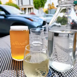 a glass of white wine and a bottle of water on a table