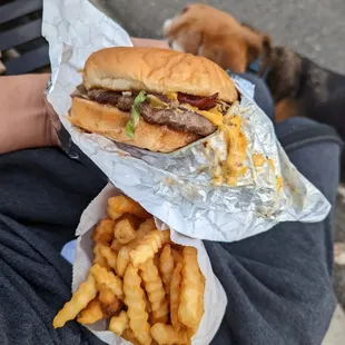 a person holding a sandwich and french fries