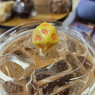 a yellow dice on top of iced coffee