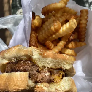 a hand holding a sandwich and french fries
