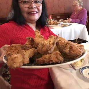 a woman holding a plate of fried chicken