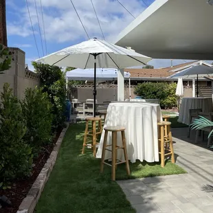 Cocktail table with market umbrella and natural barstools