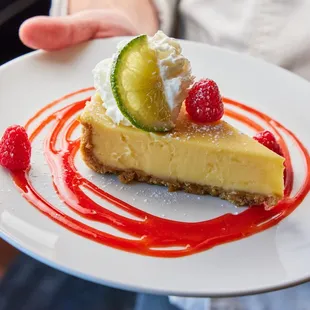 a piece of cheesecake with raspberries and whipped cream