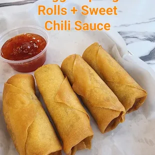 a plate of vegetable spring rolls and a bowl of chili sauce